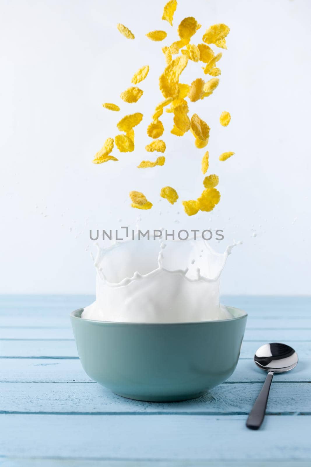 Healthy Breakfast-Cornflakes and Milk Splash on blue background.