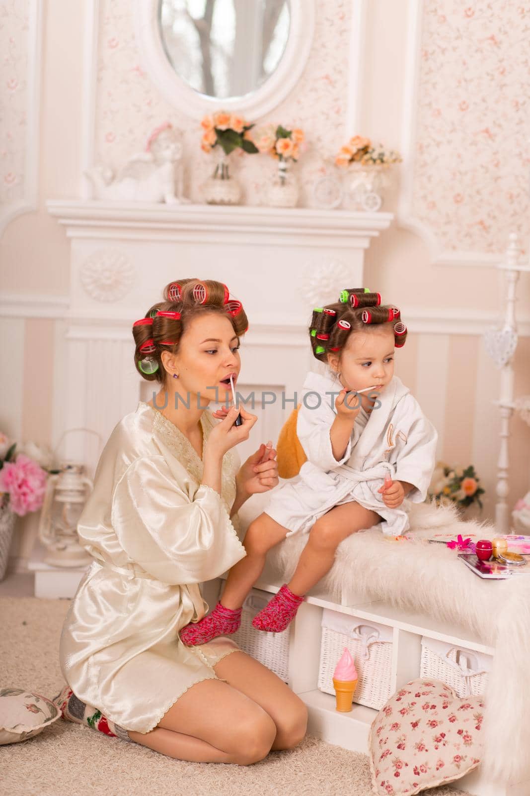 Adorable little girl with her mother in hair curlers apply makeup. Mom teaches daughter to use cosmetics. Beauty day. Girls are such girls by Try_my_best
