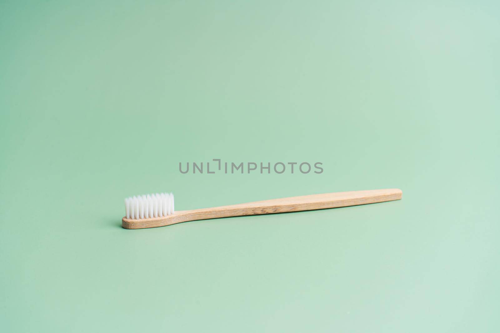 Environmentally friendly bamboo wood antibacterial toothbrush on light green background by Try_my_best