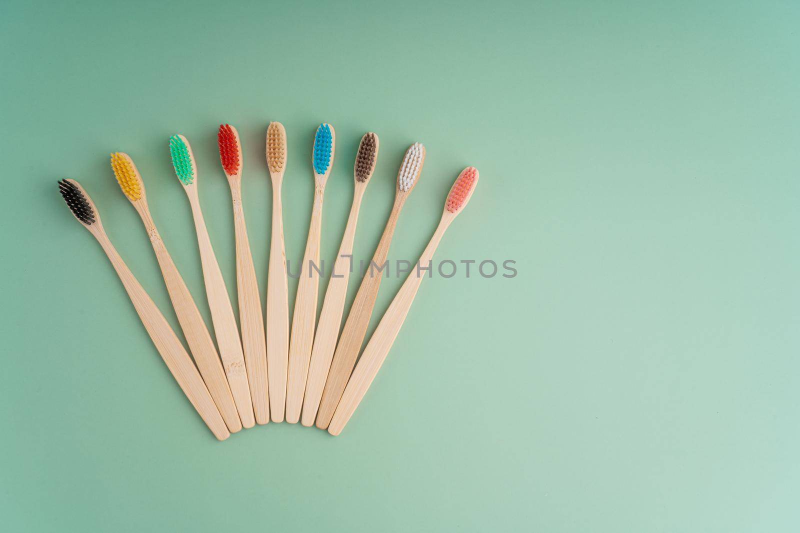 A set of Eco-friendly antibacterial toothbrushes made of bamboo wood on a light green background. Environmental care trends.