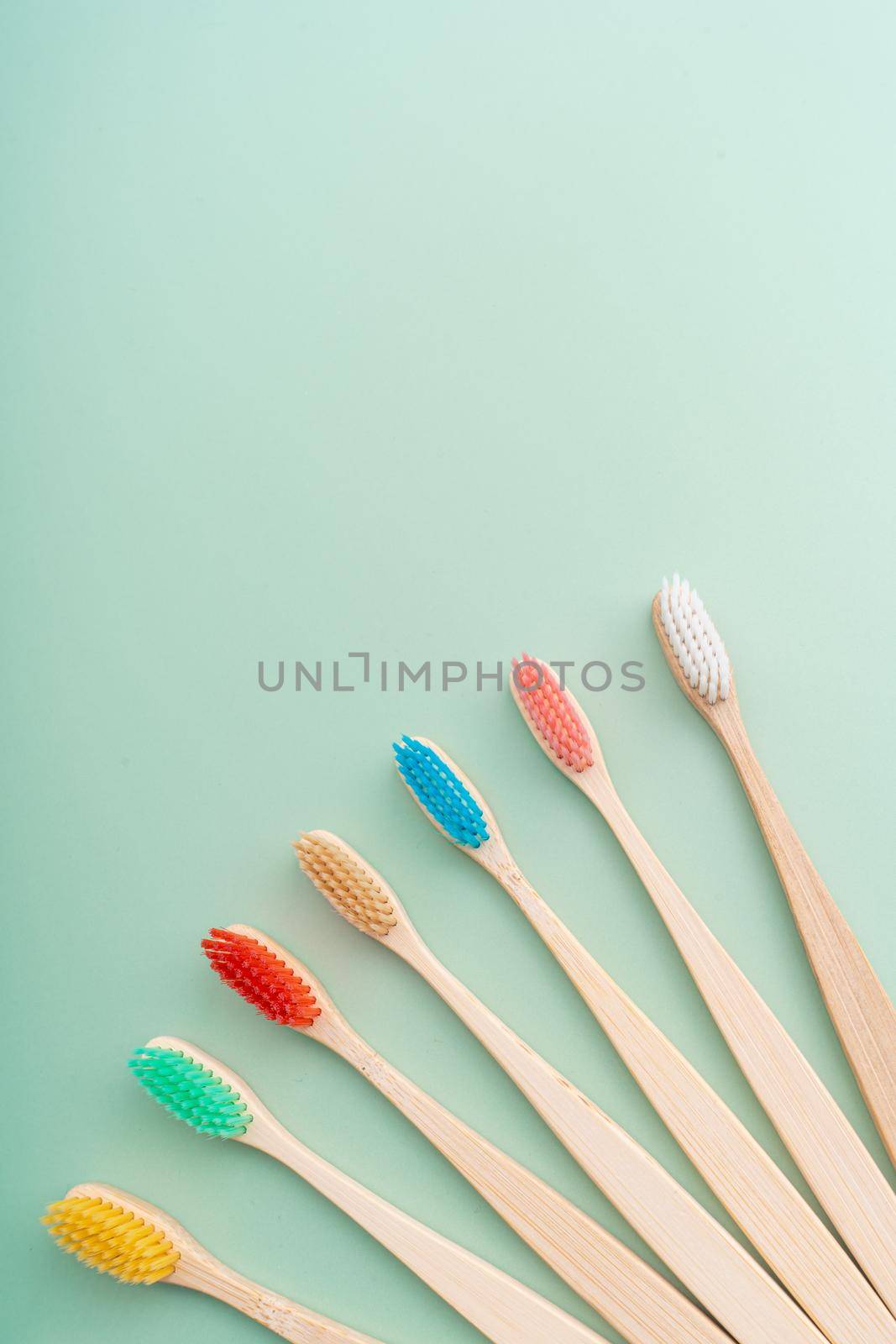 A set of Eco-friendly antibacterial toothbrushes made of bamboo wood on a light green background. Environmental care trends.