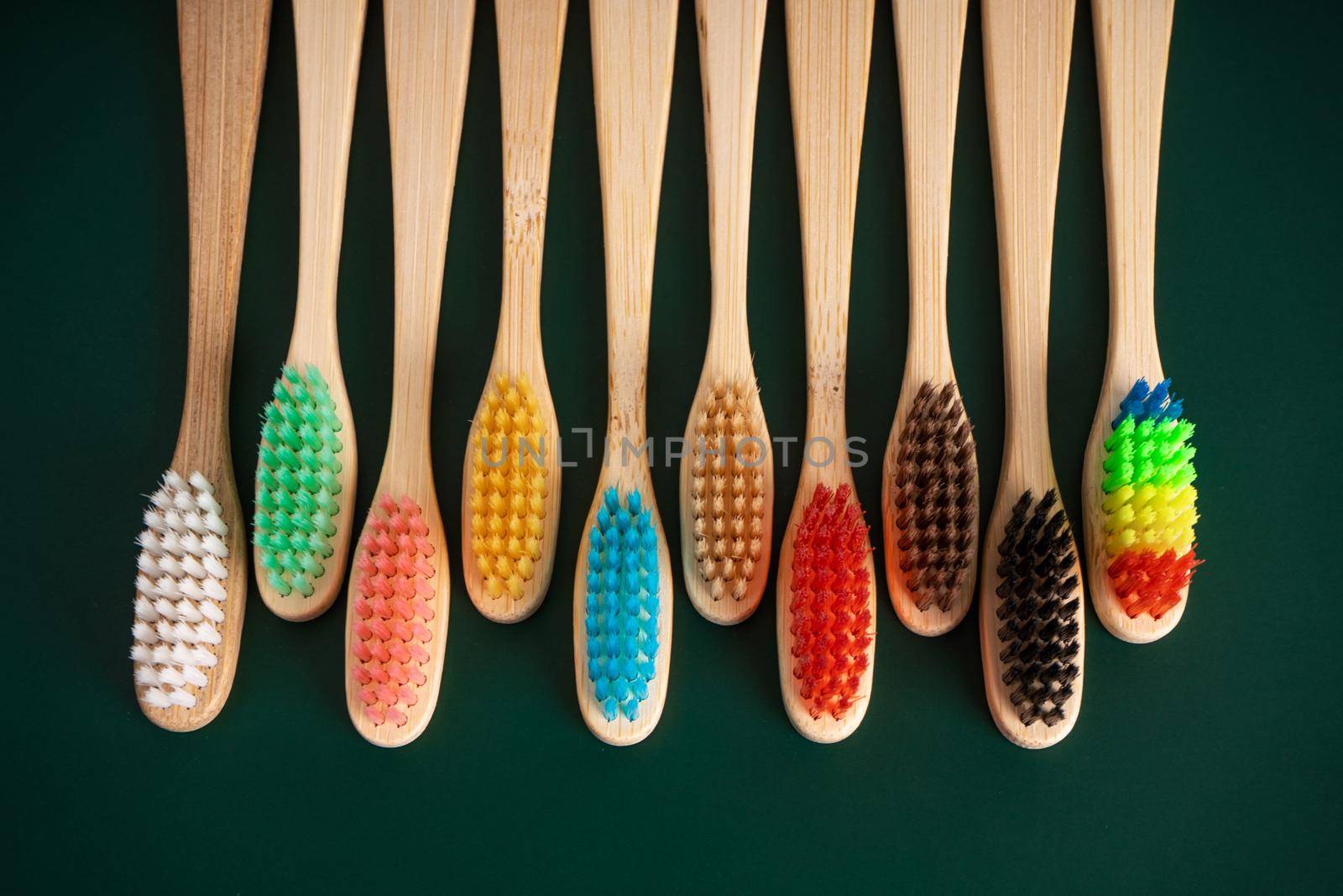 A set of Eco-friendly antibacterial toothbrushes made of bamboo wood on a dark green background. Environmental trends by Try_my_best