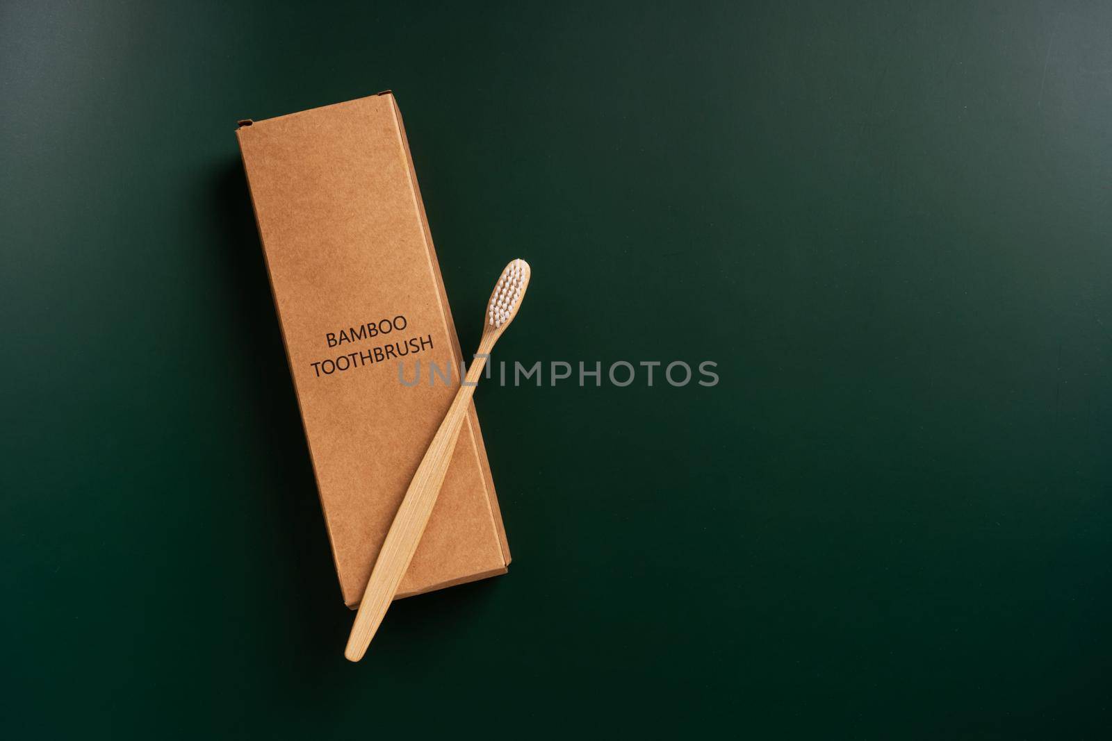 Eco-friendly antibacterial bamboo wood toothbrush on dark green background. Taking care of the environment in trend by Try_my_best