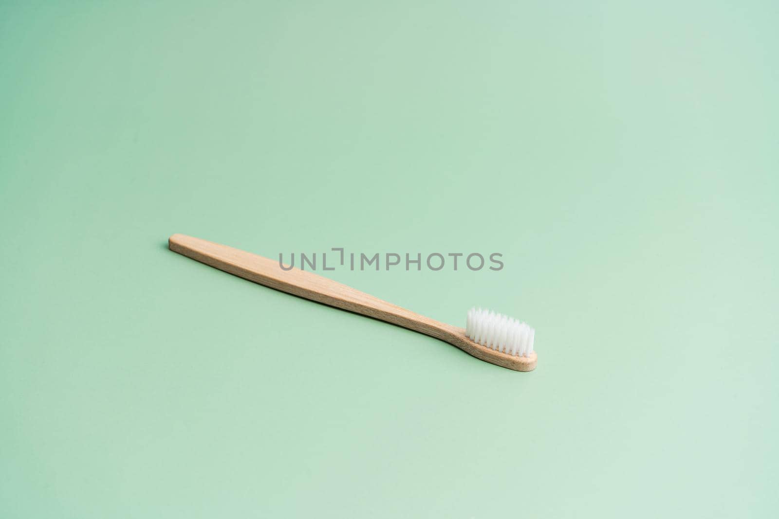 Environmentally friendly bamboo wood antibacterial toothbrush on light green background by Try_my_best