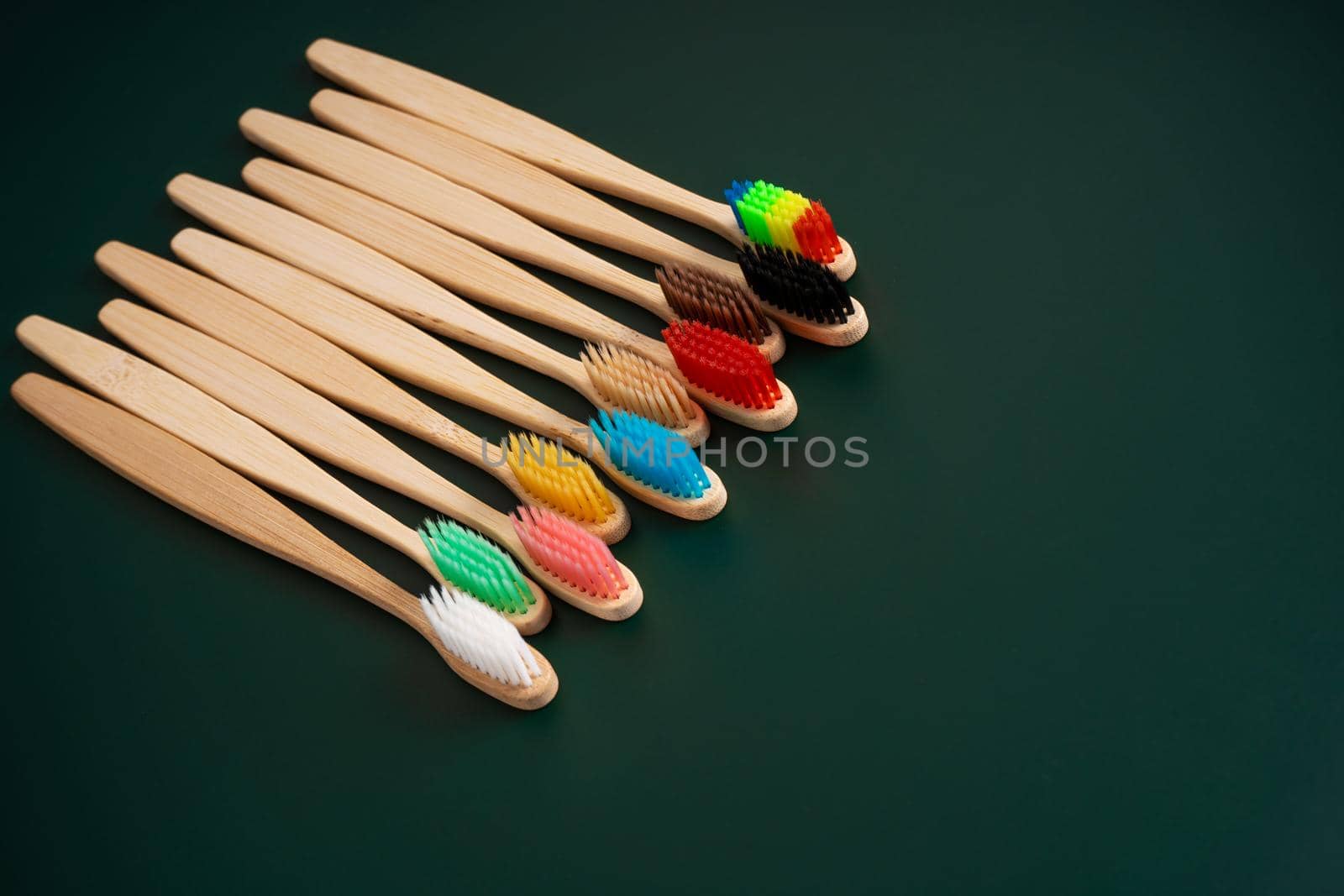 A set of Eco-friendly antibacterial toothbrushes made of bamboo wood on a dark green background. Environmental trends by Try_my_best