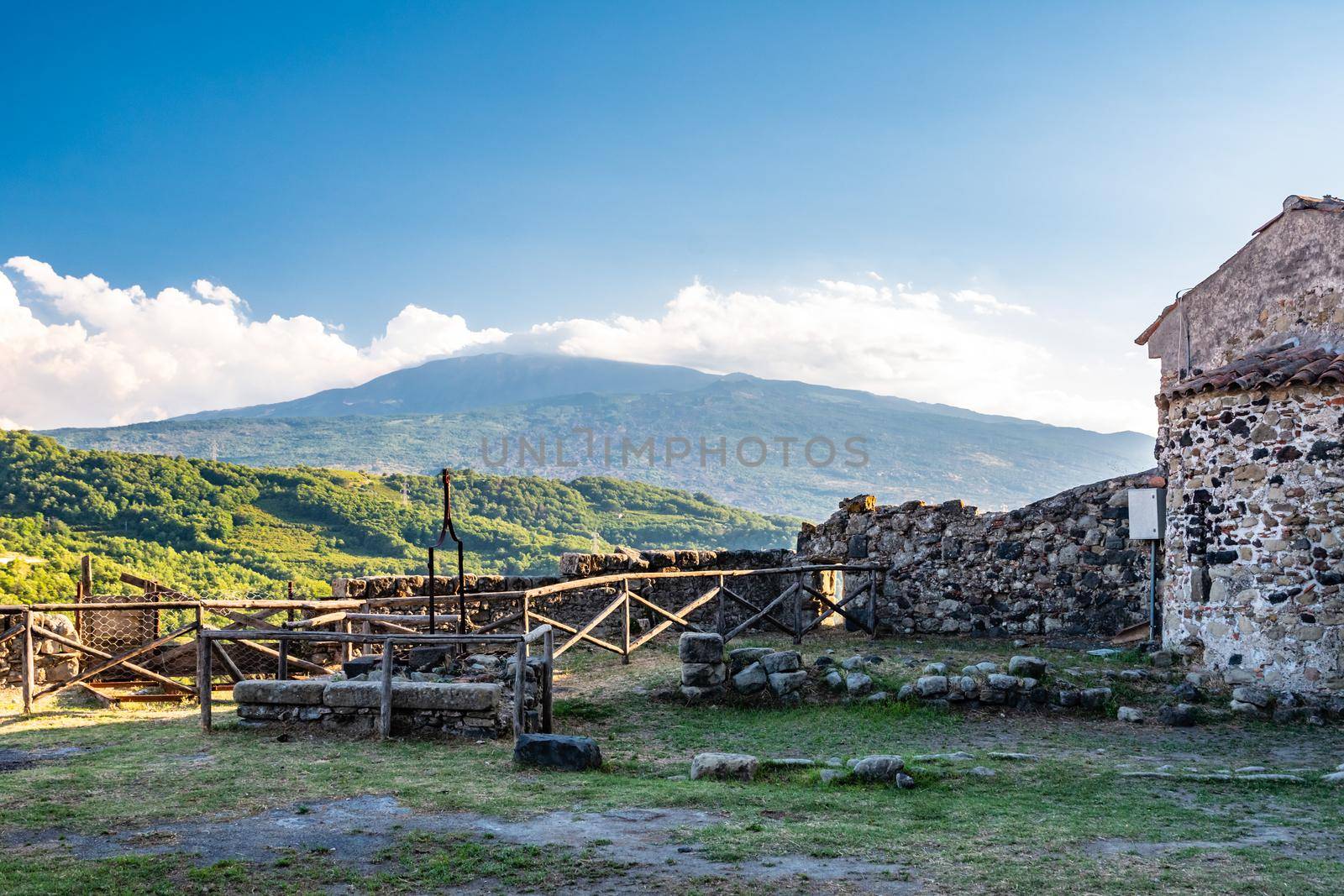 Smoking Mount Etna Volcano from Lauria Castle terrace illuminated by afternoon sun in Castiglione di Sicilia, Italy