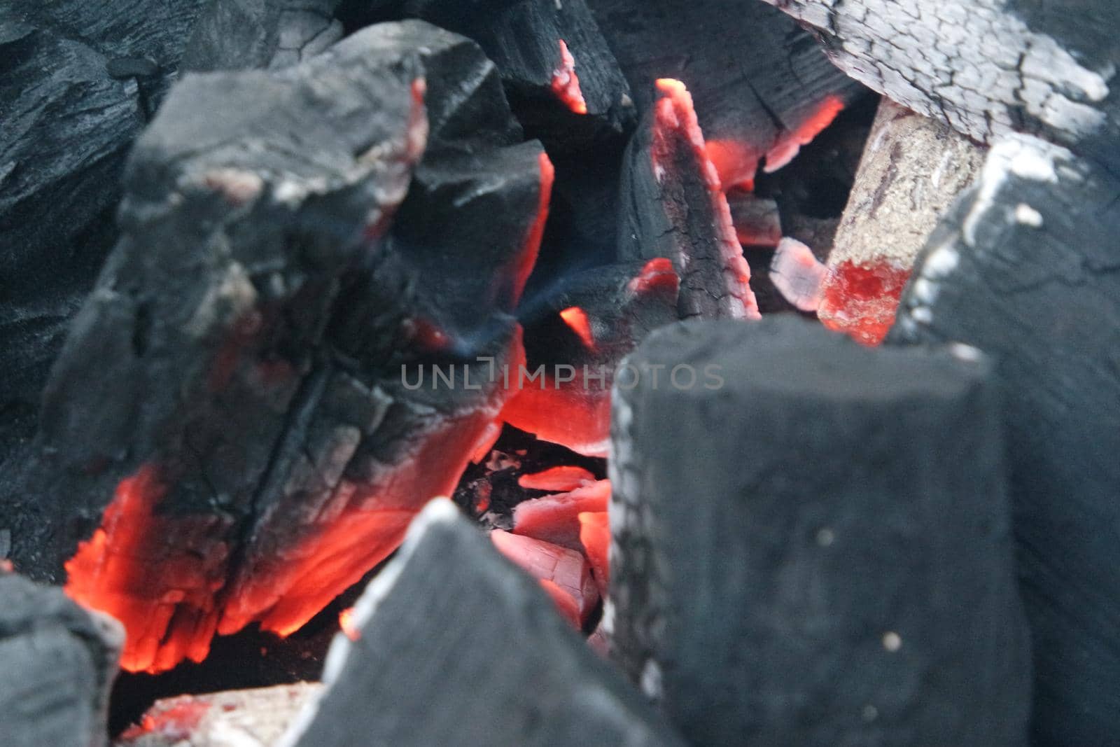 Fire on logs in fire pot with embers and burning coal and blazing flames. by Photochowk