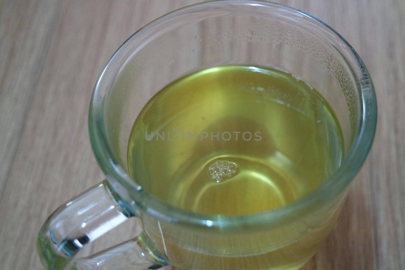 Glass cup having brewed fragrant green tea or qehwa or qahwa on the wooden floor. It is served with sugar or honey and nuts