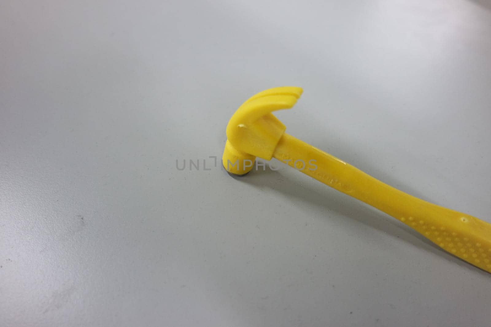 Selective focused, closeup view of toy hammer made from plastic placed on metal background