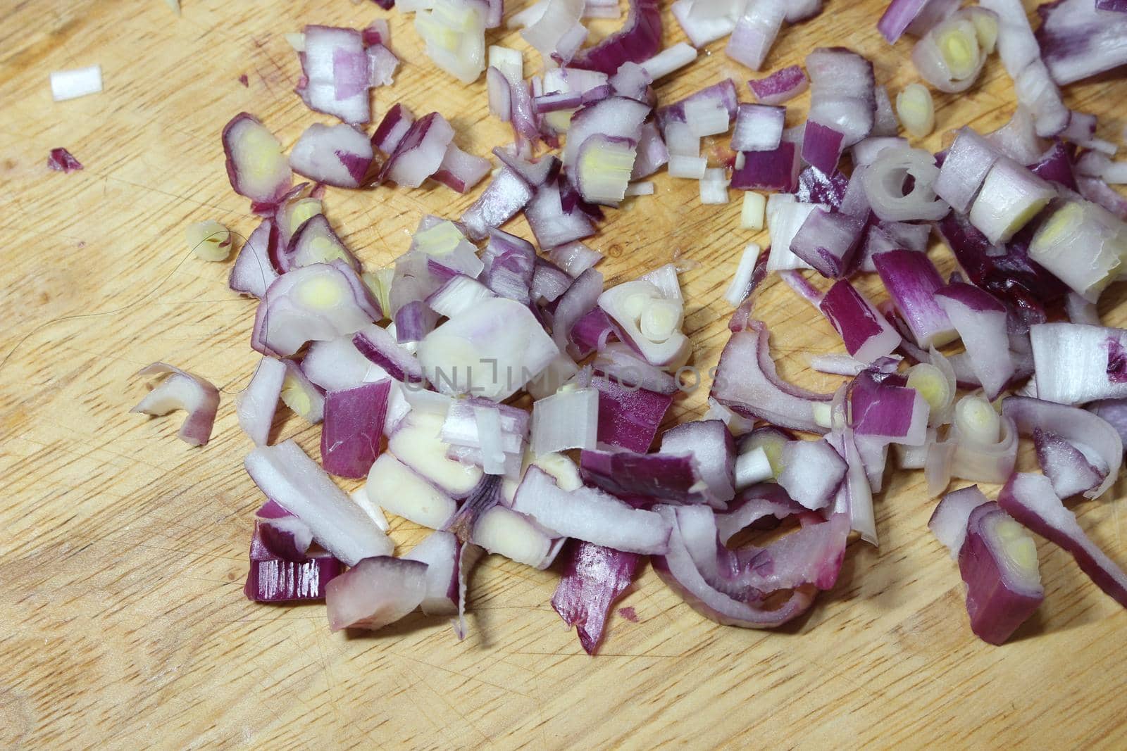 Chopped white onion with sharp knife on wooden cutting board by Photochowk