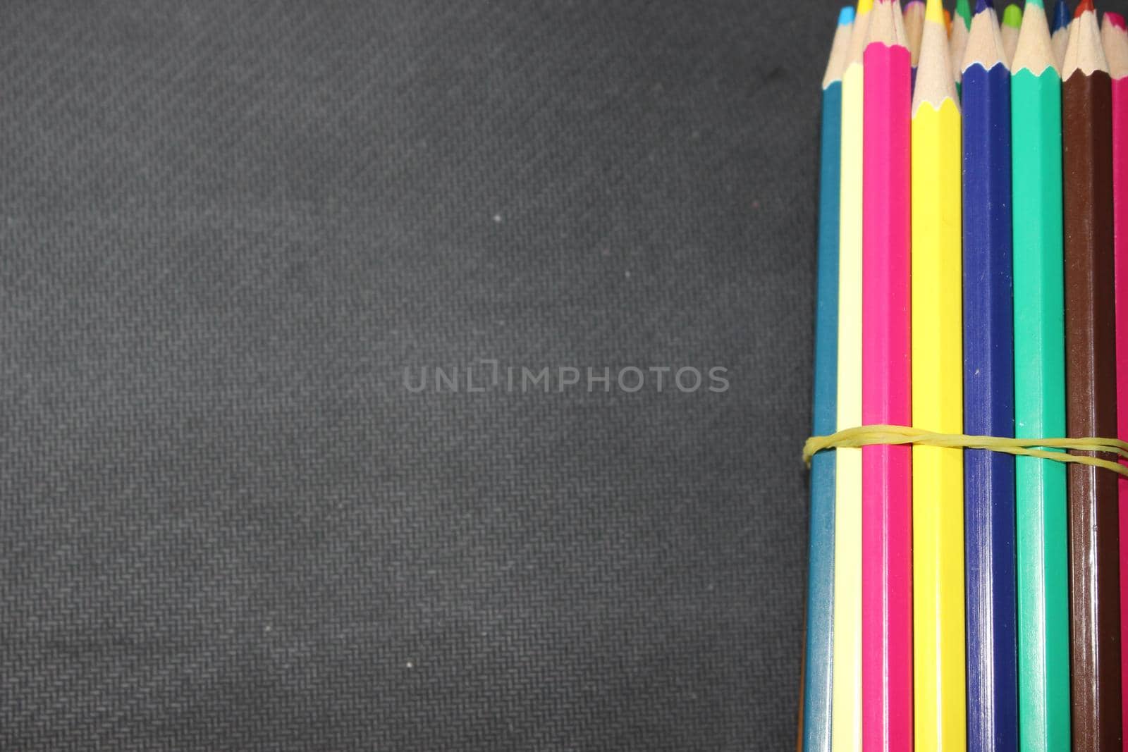 Bright colored multicolor pencils on black background by Photochowk