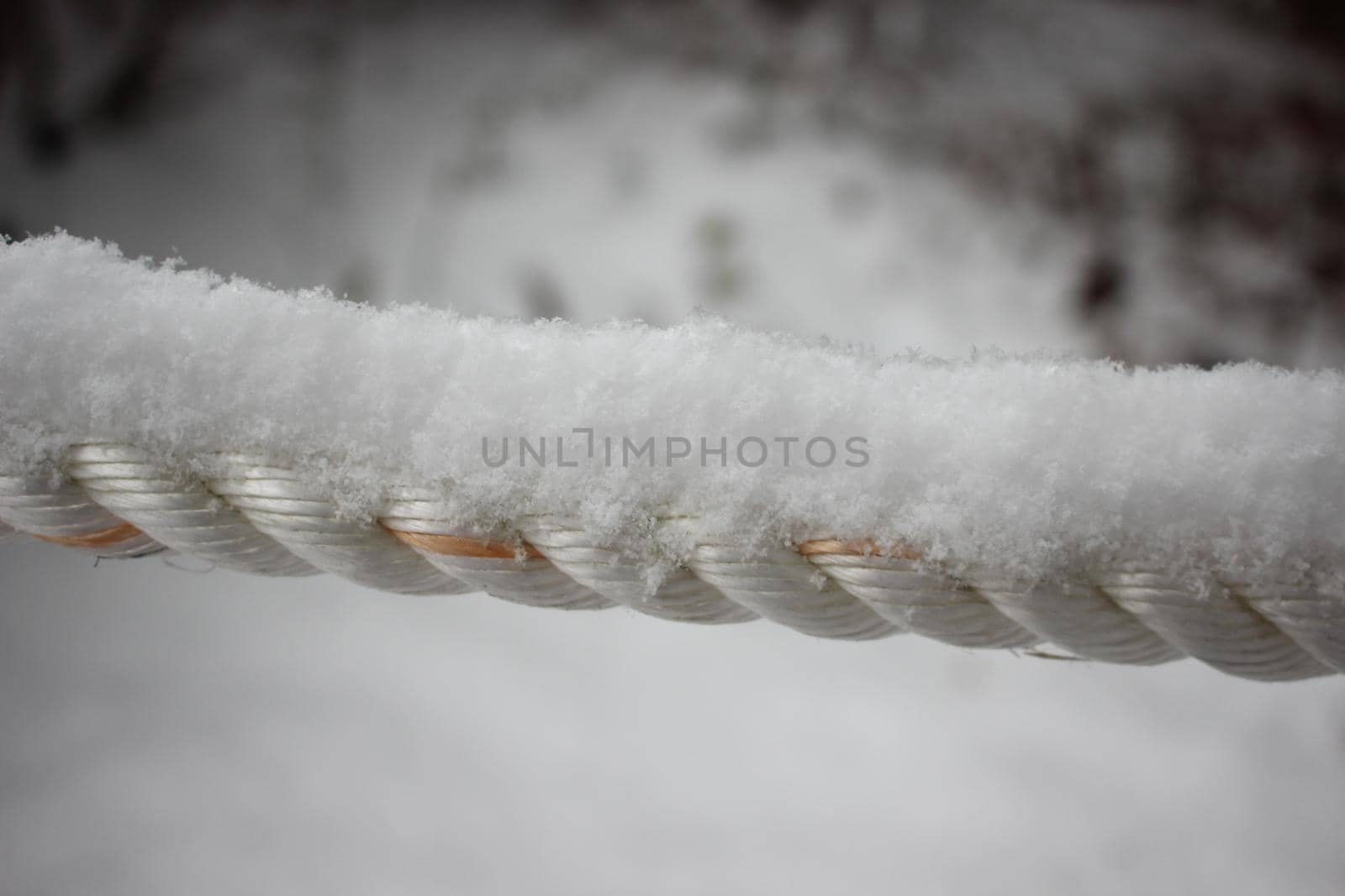 Snow flakes on rope in winter snowfall. Closeup macro view of snow on rope