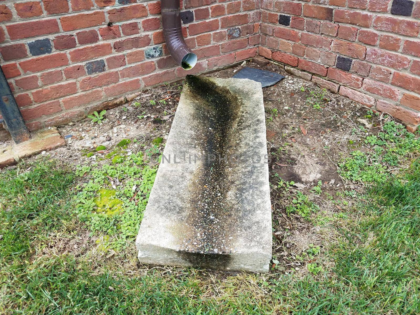 rain gutter downspout or pipe and cement slab with brick wall