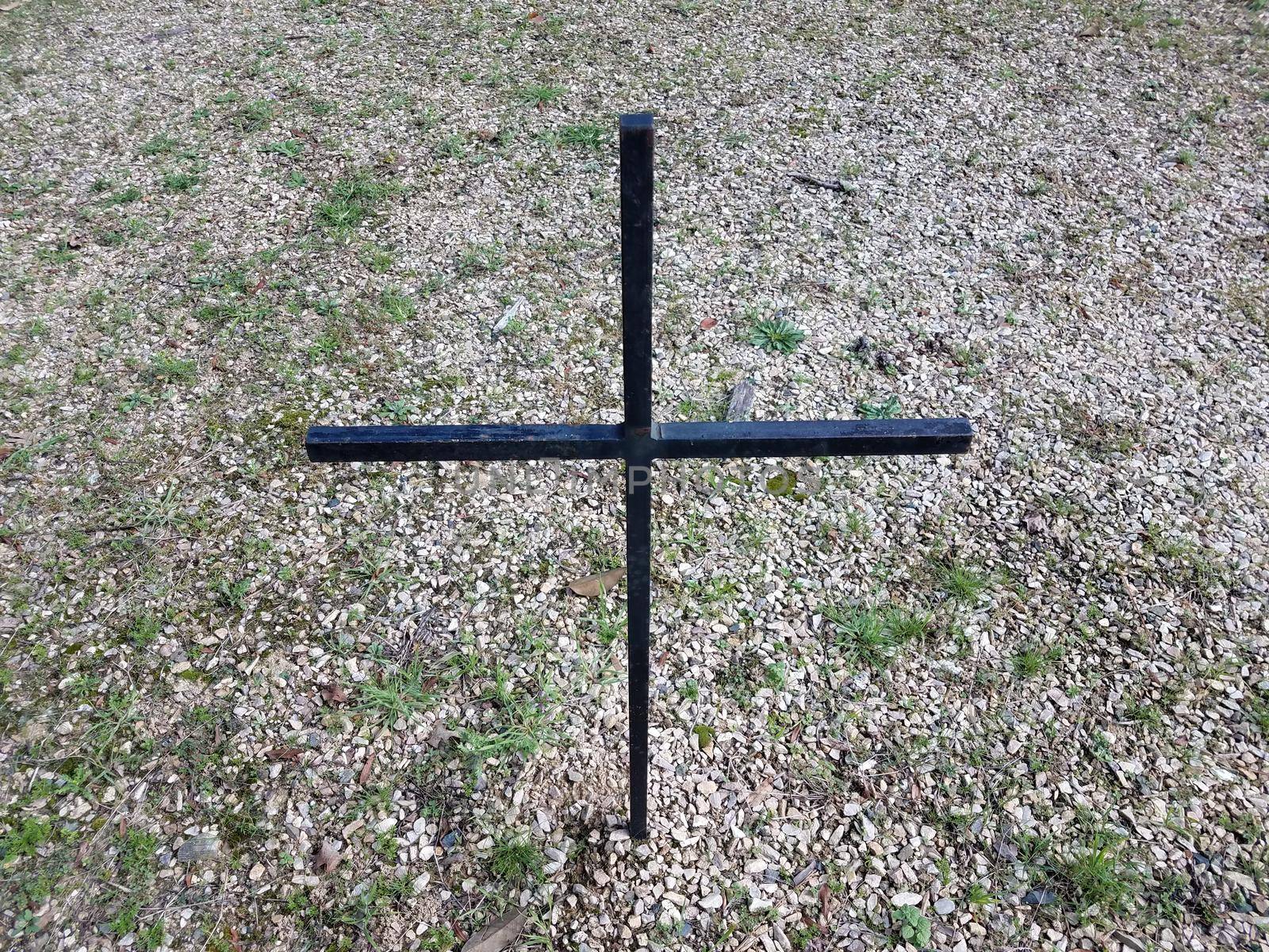 black cross in lawn or yard with stones or pebbles