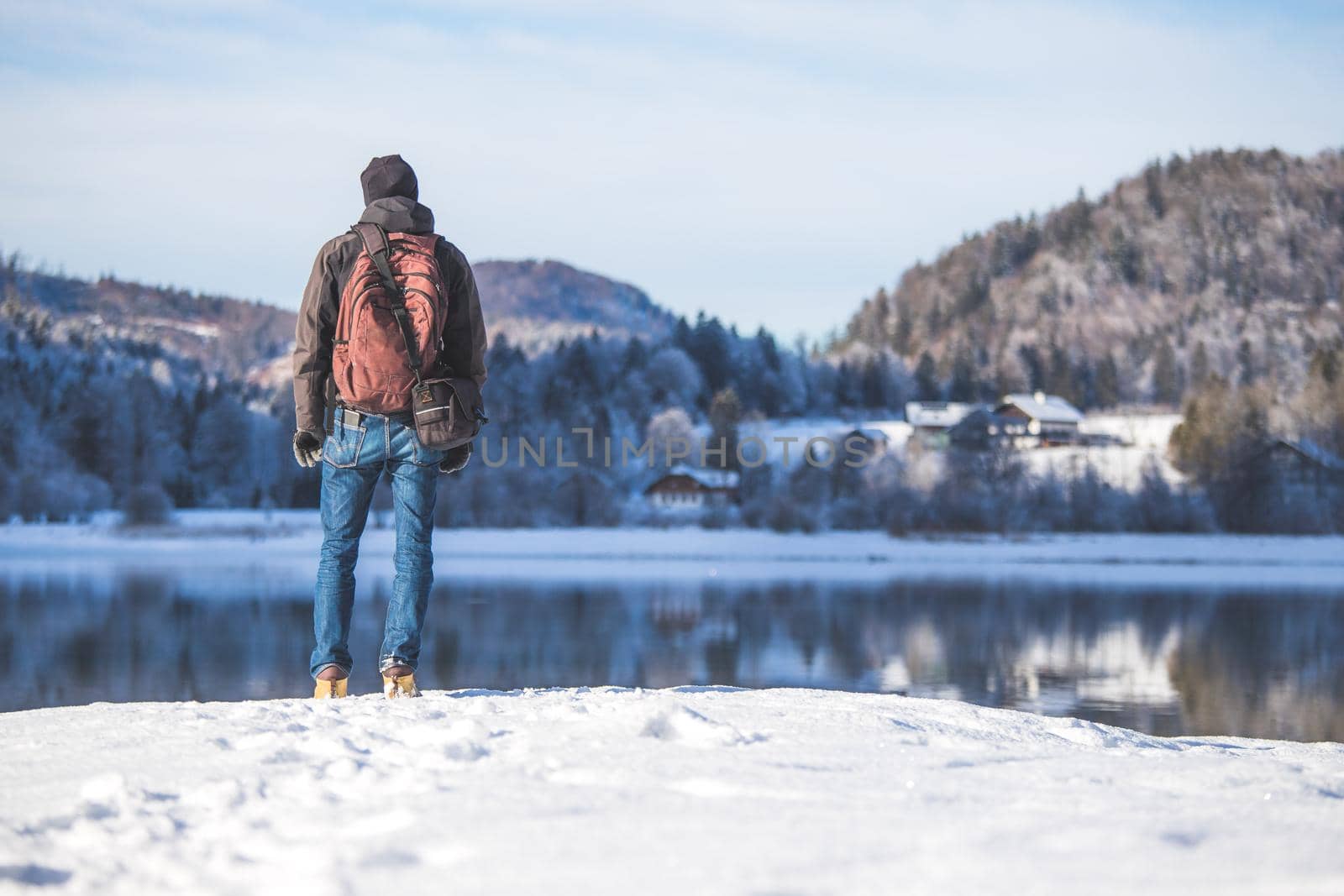 Sporty Caucasian man is at the lakeshore, enjoying the view. Winter landscape.