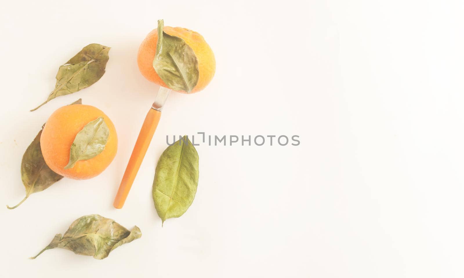 Tropical fruit composition.Top view, minimalistic tangerines with leaves and a knife for cutting on white background,copyspace. 