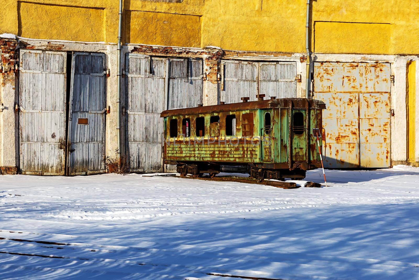 Old railway carriage in a depot on the background of a building with a gate by seka33