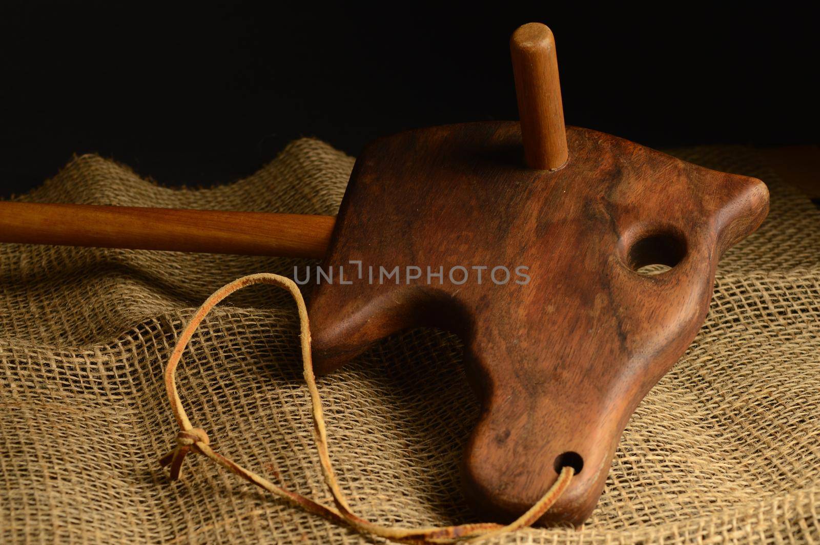 A closeup of an antique wooden horse toy over some brown burlap fabric.