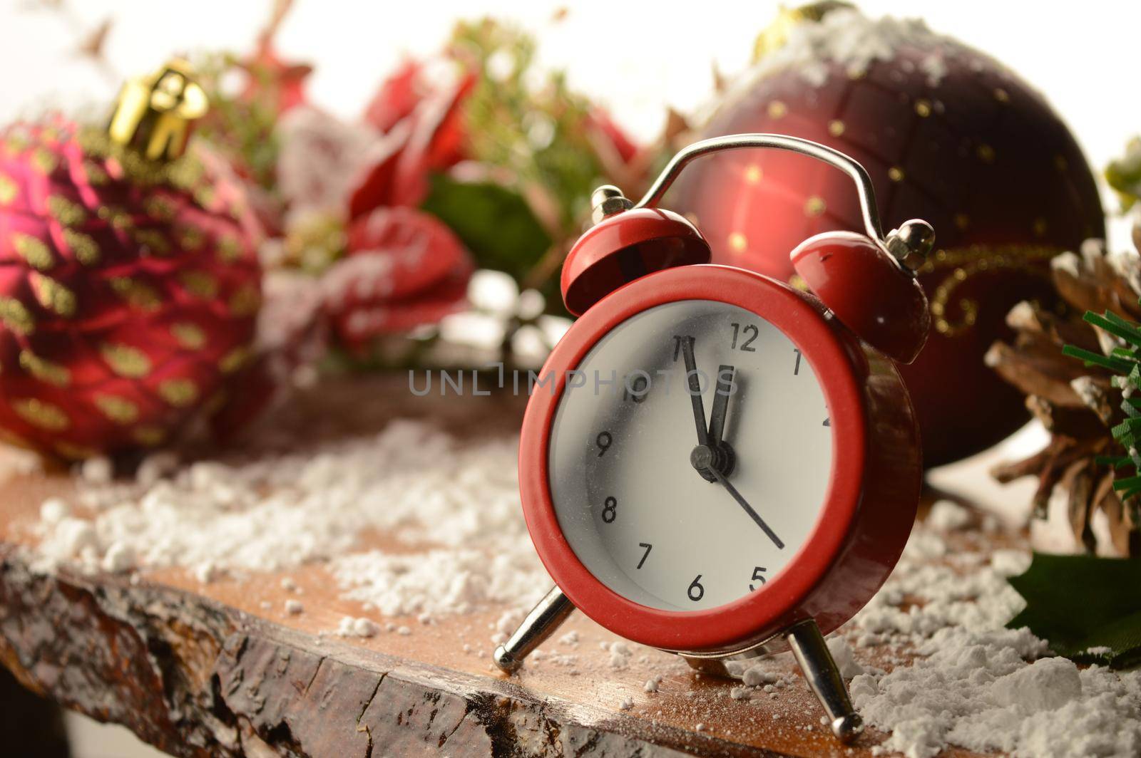 The countdown to midnight on New Years Eve is the focus used here with a red alarm clock and festive holiday setting.