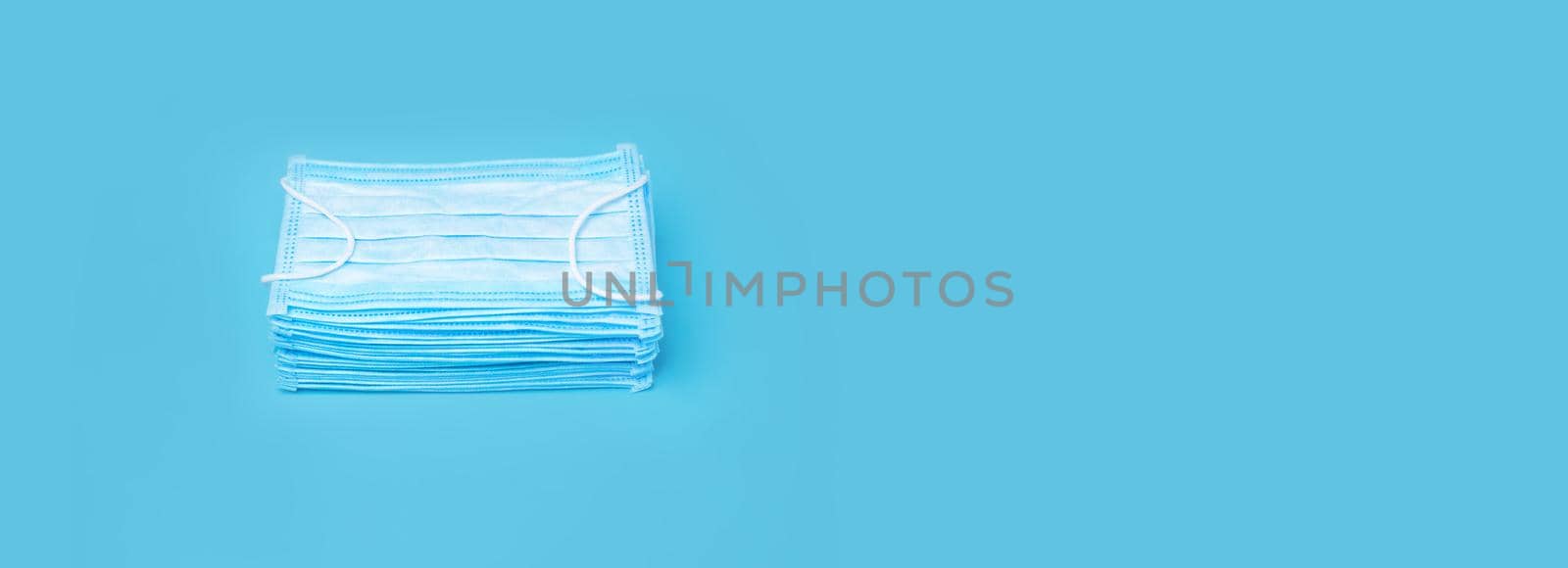 Masks on Blue Background with Copy Space. Stacked Medical Mask. Prevention Concept. Pile Mask. Set Disposable Mask. Many Blue 3-ply Surgical Mask. Prevention Concept. Protection against Coronavirus by synel