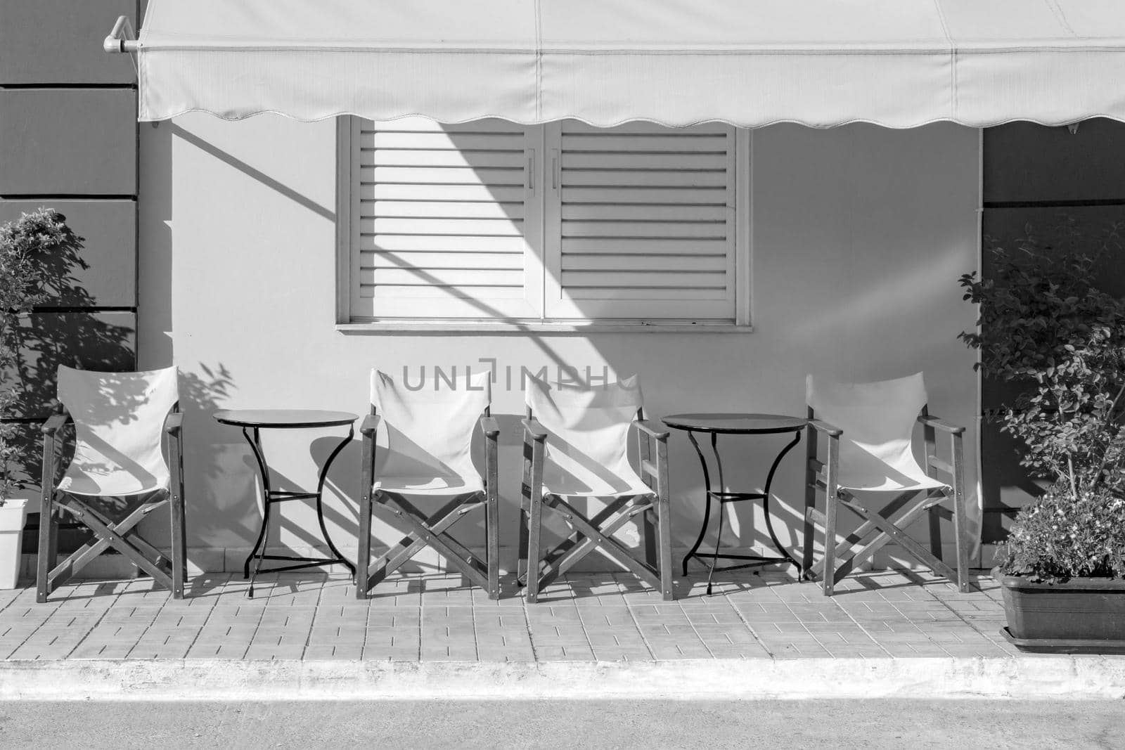 Front view of cafe exterior. Typical cafe. Empty chairs with table near coffee shop. Empty touristic place. Closed cafe. Black and white photos cafe. b w street. Restaurant black and white. no visitor