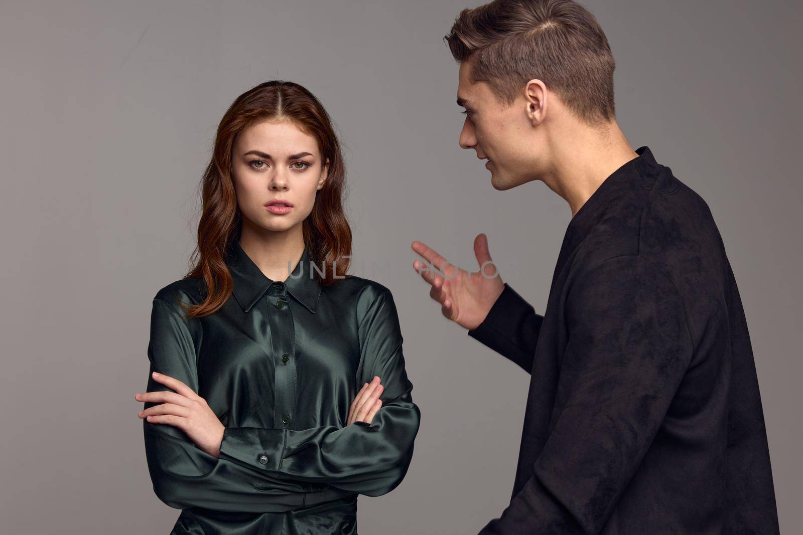 An indignant man in a black jacket gestures with his hands and looks at the woman. High quality photo