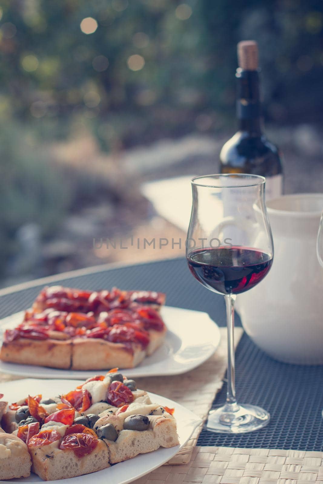 Italian Dinner with red wine, pizza and bread outside. Vacation