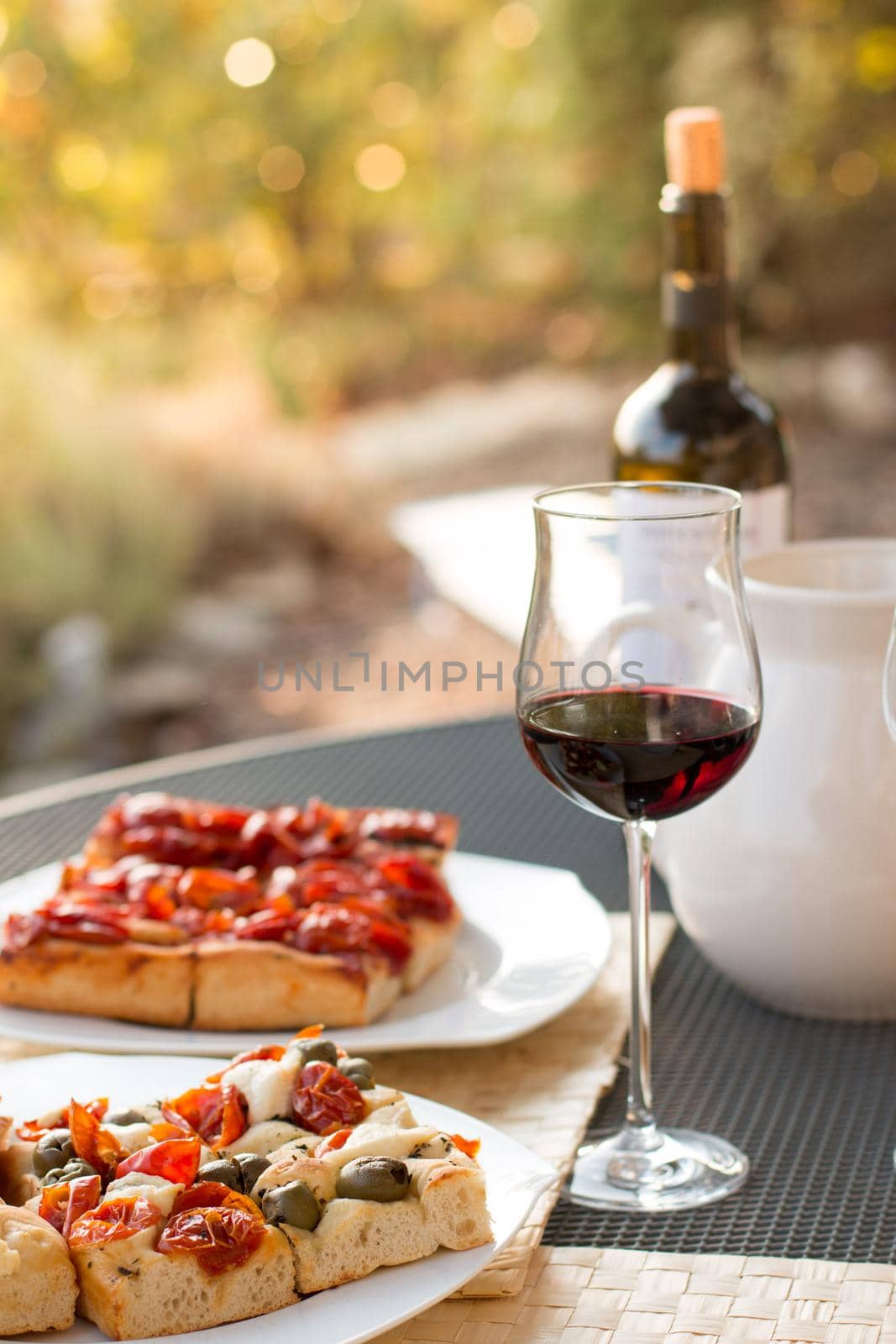 Italian Dinner with red wine, pizza and bread outside. Vacation