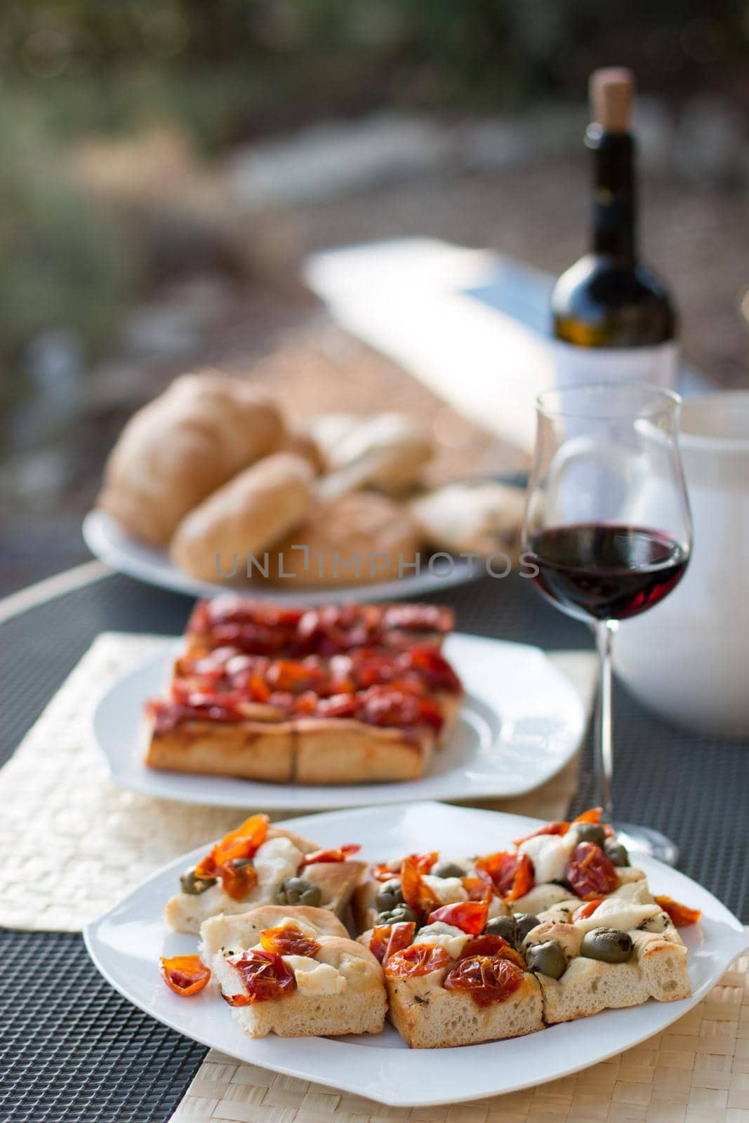 Italian Dinner with red wine, pizza and bread outside. Vacation