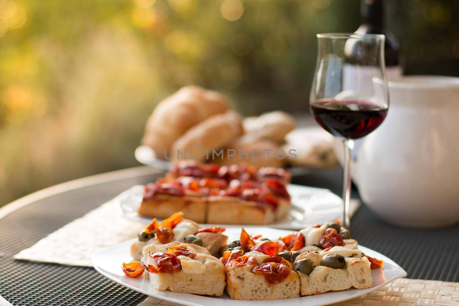 Italian Dinner with red wine, pizza and bread outside. Vacation