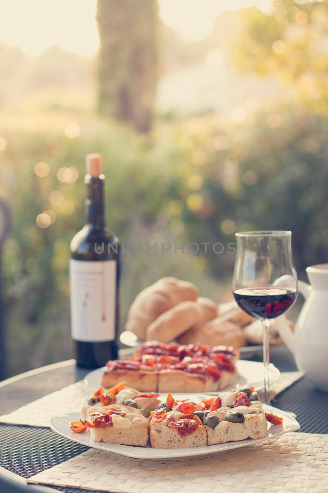 Italian Dinner with red wine, pizza and bread outside. Vacation