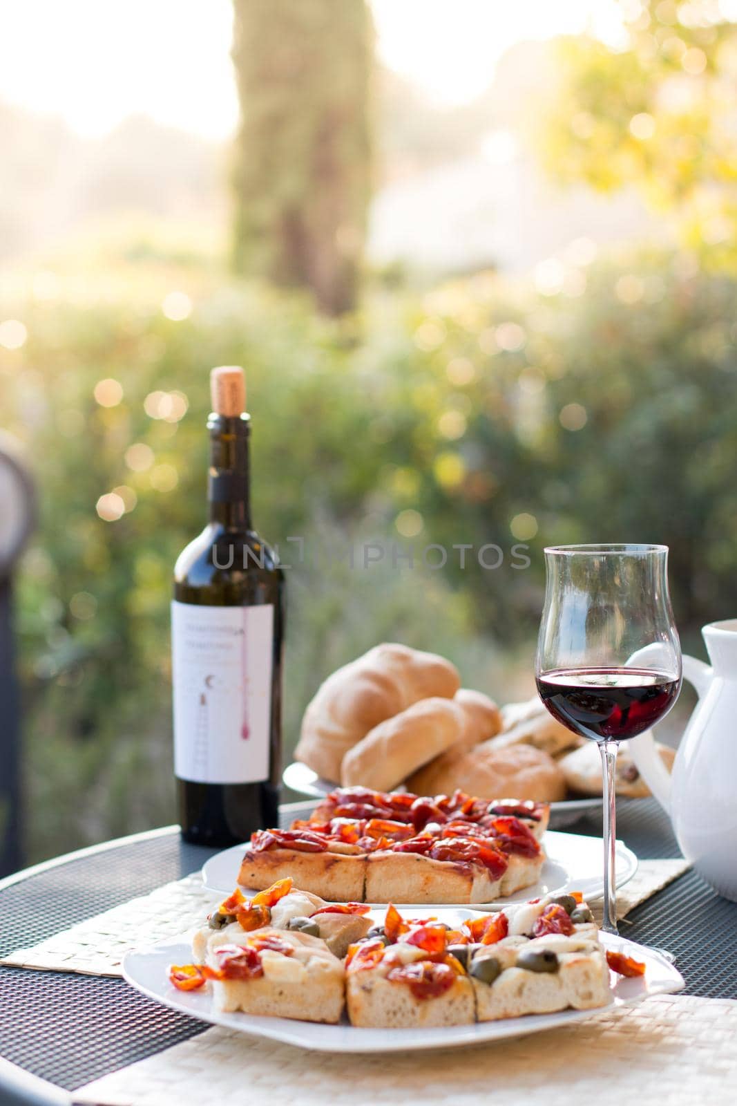 Italian Dinner with red wine, pizza and bread outside. Vacation