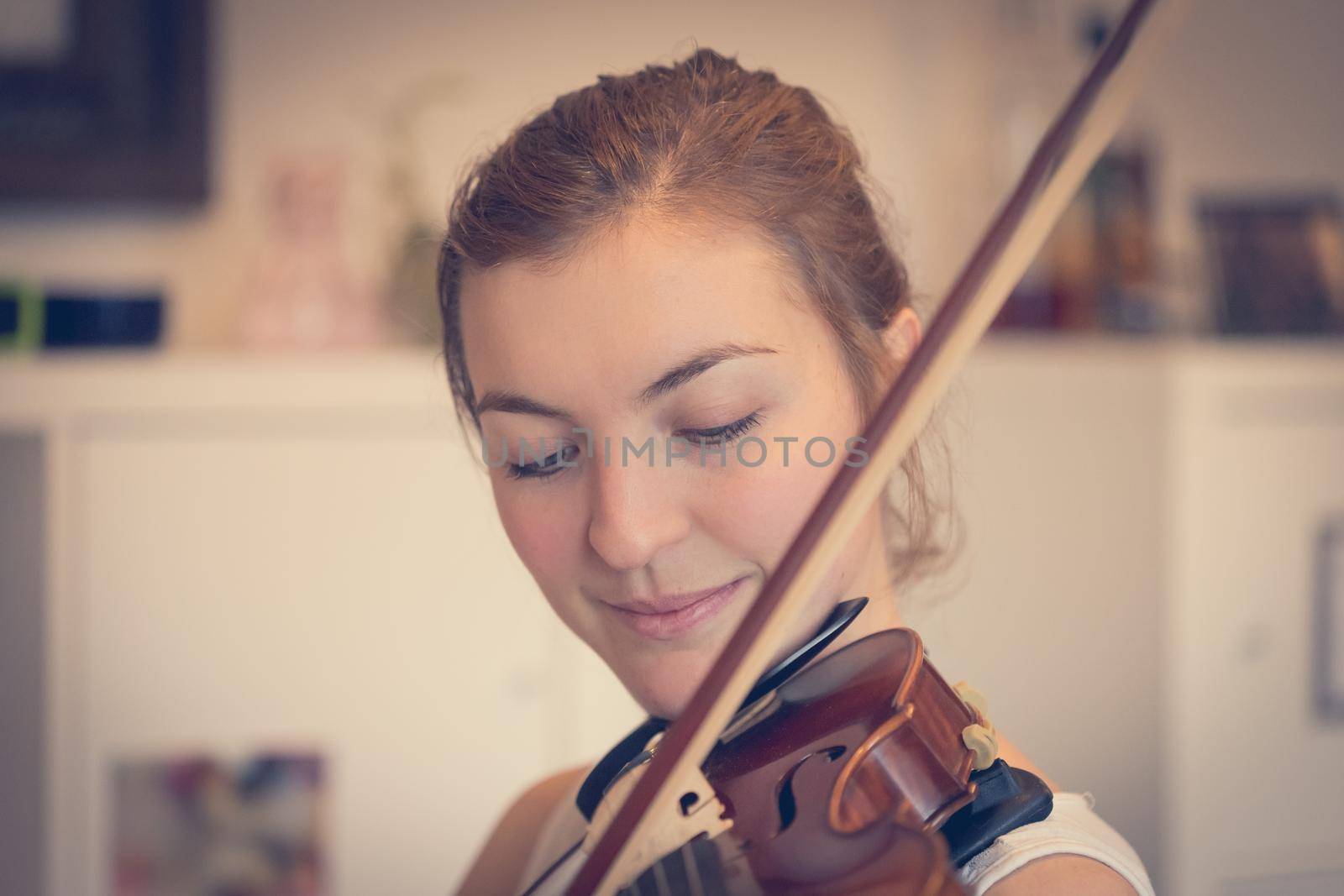 Young girl happily plays on her violin by Daxenbichler