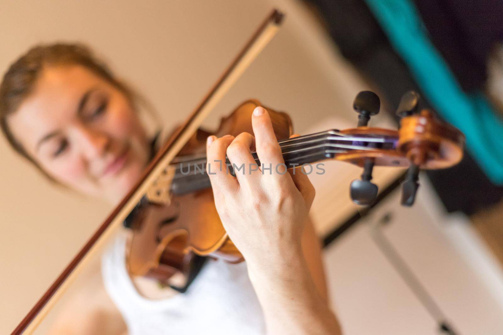 Young girl happily plays on her violin by Daxenbichler