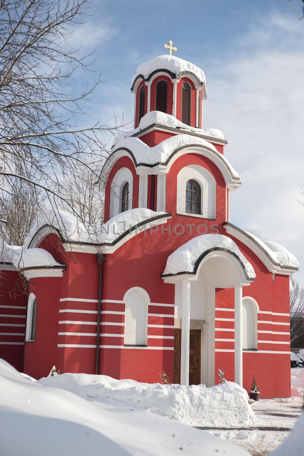 Red Christian church in the winter, snow on the roof by Daxenbichler