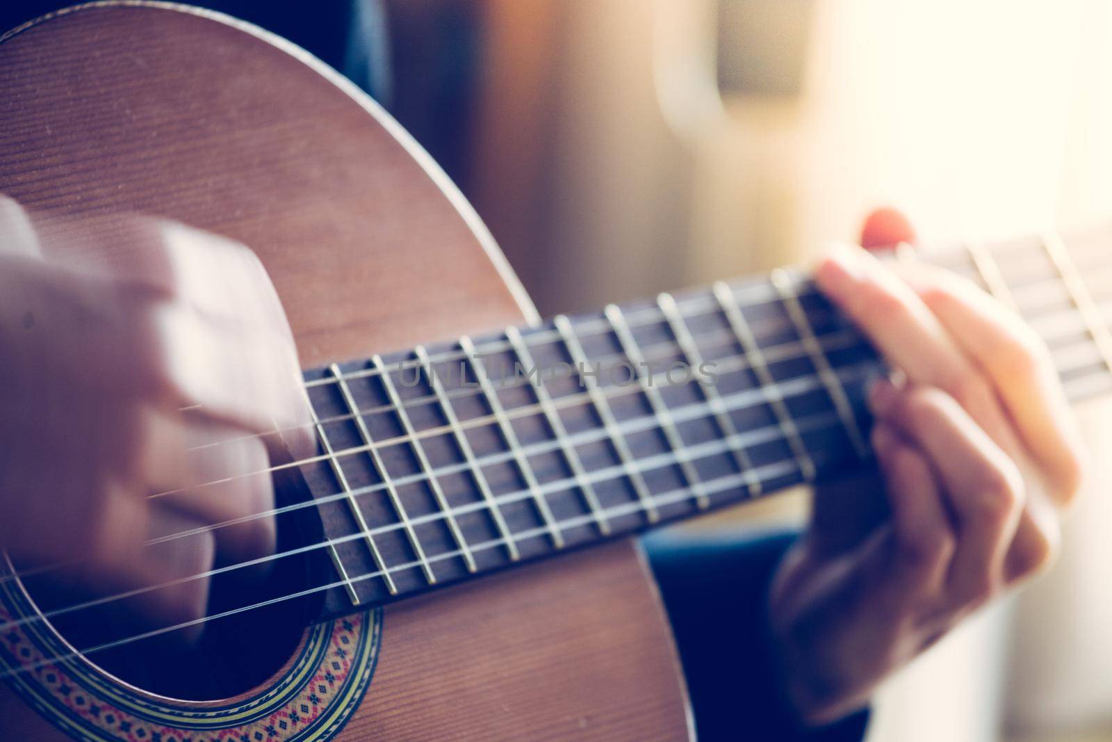 Musician plays a classical guitar, blurry hands, fretboard and fingers