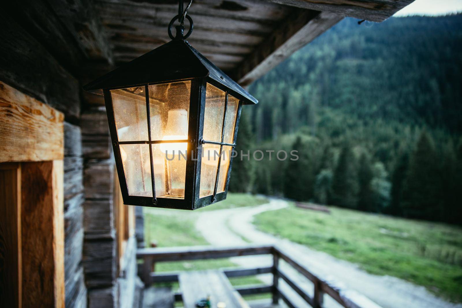 Rustic lantern is shining over the veranda, alpine hut