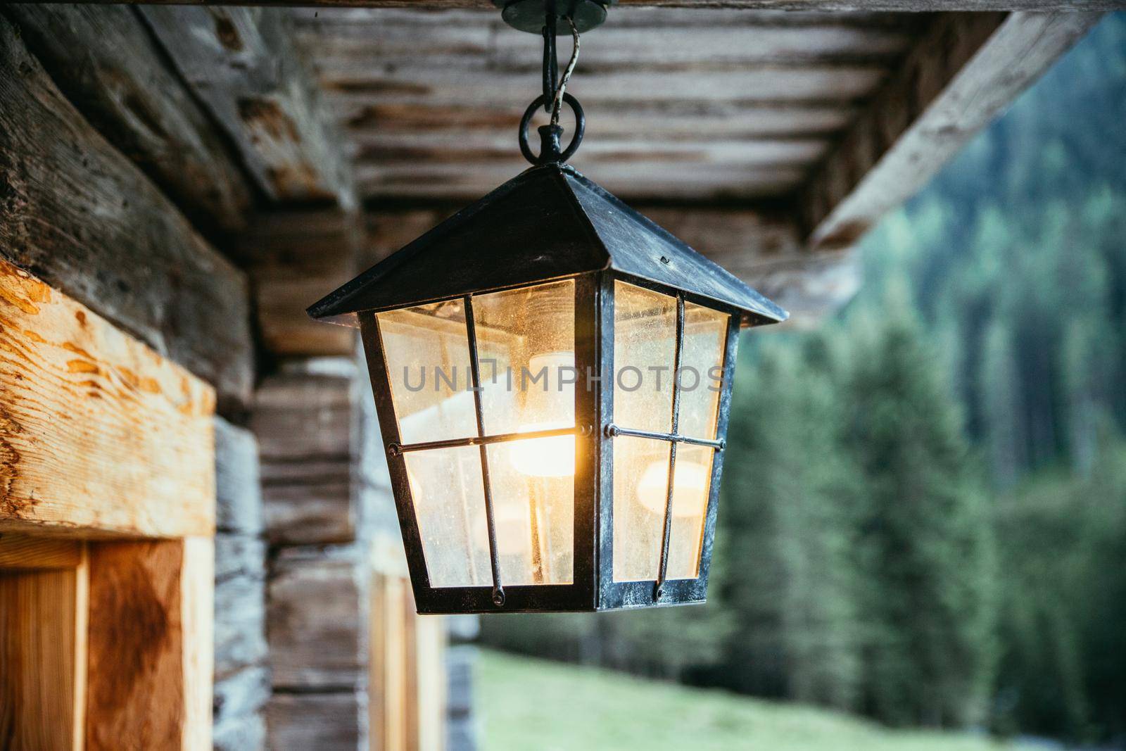 Rustic lantern is shining over the veranda, alpine hut