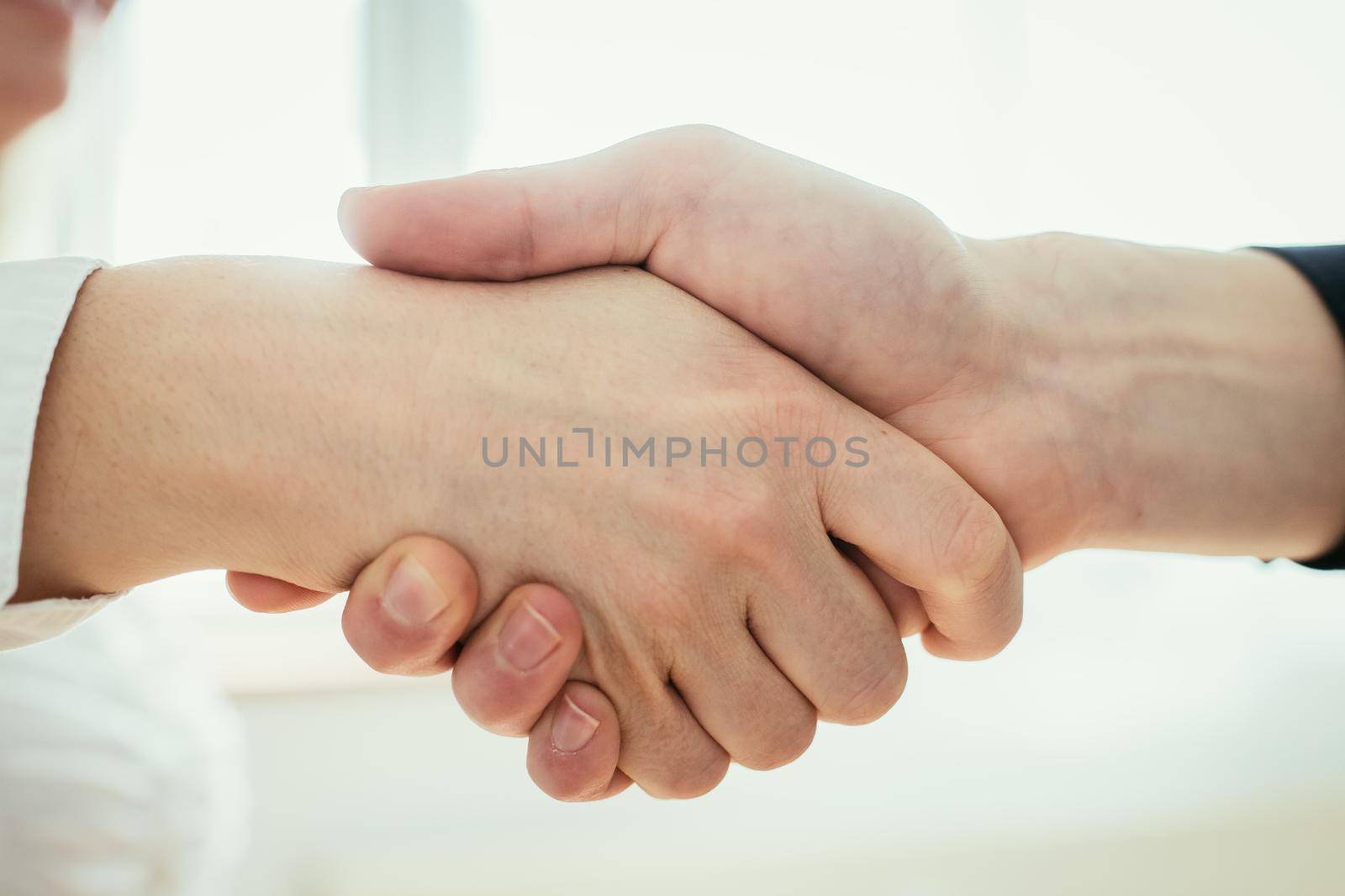 Shaking hands, concept for teamwork: Close up of man and woman shaking hands in the office by Daxenbichler