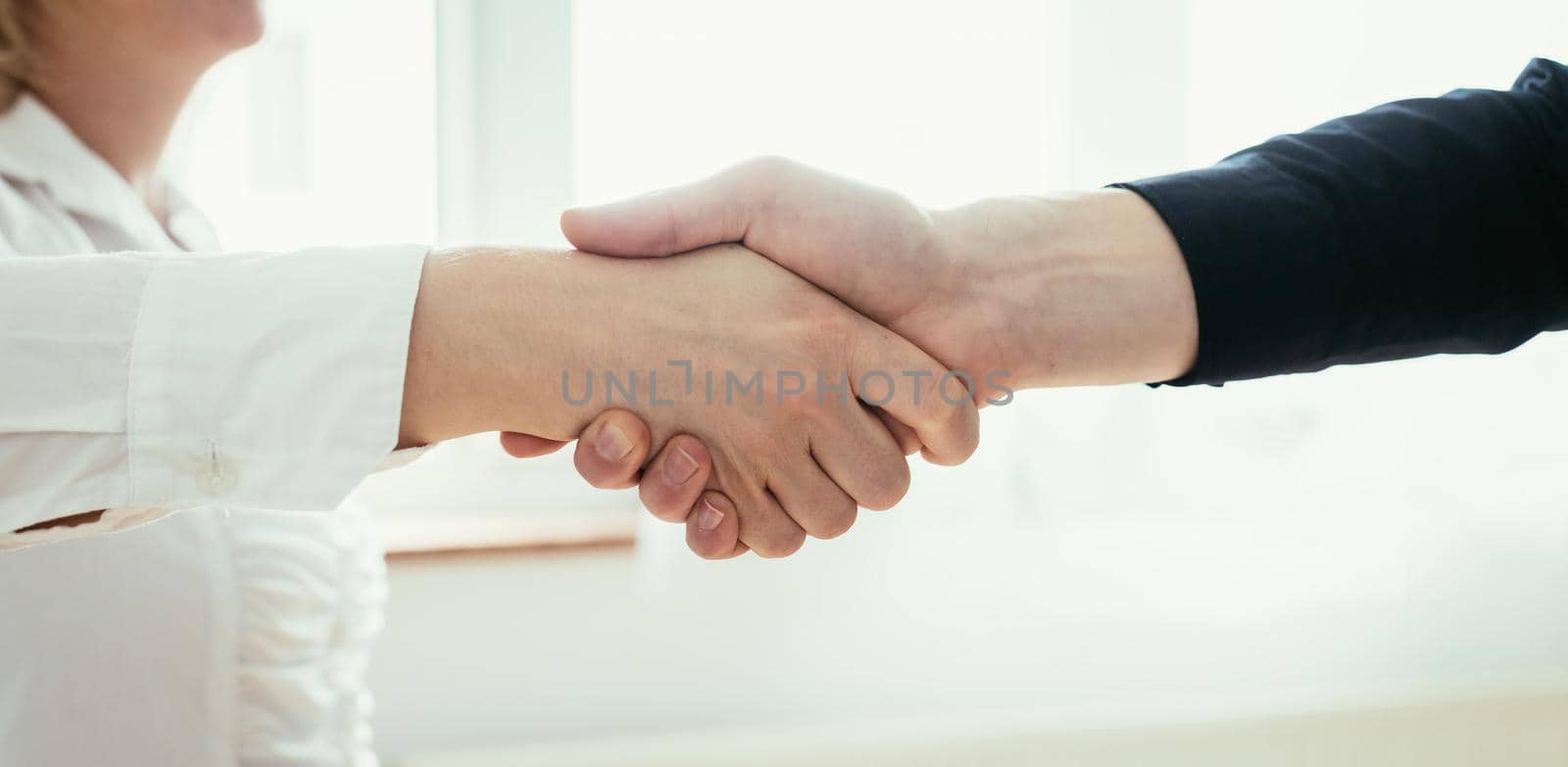 Shaking hands, concept for teamwork: Close up of man and woman shaking hands in the office by Daxenbichler