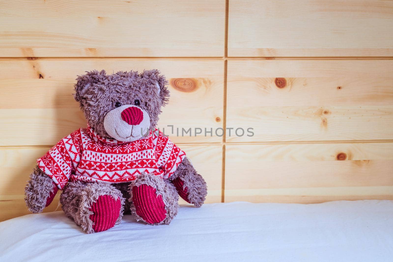 Cute teddy bear toy is sitting in the bed, wakeup at morning