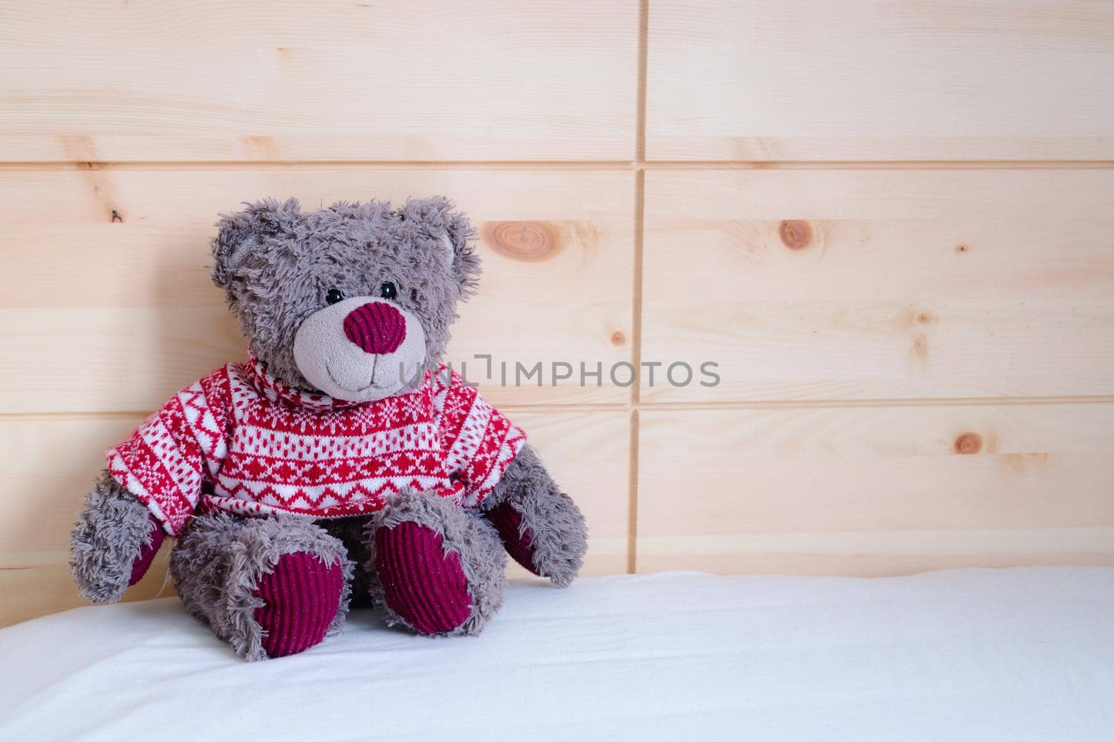 Cute teddy bear toy is sitting in the bed, wakeup at morning