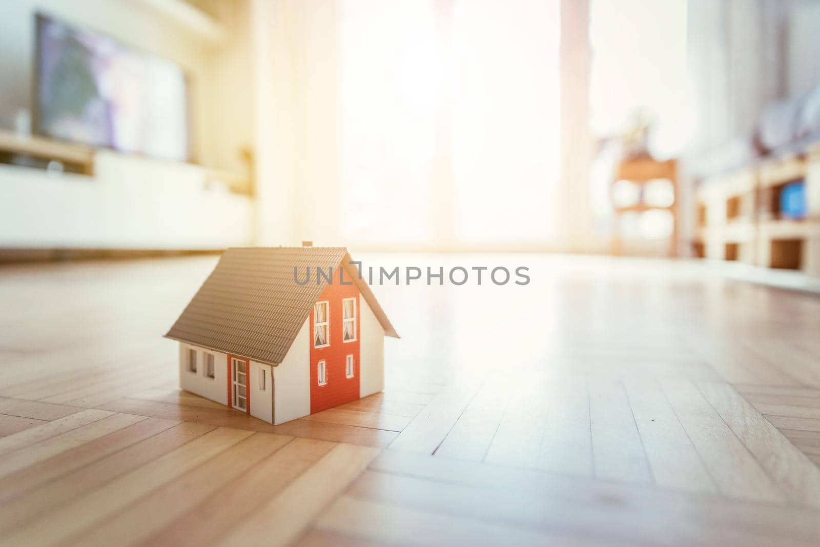 Red house model on the floor, indoors. Concept for new home, property and estate