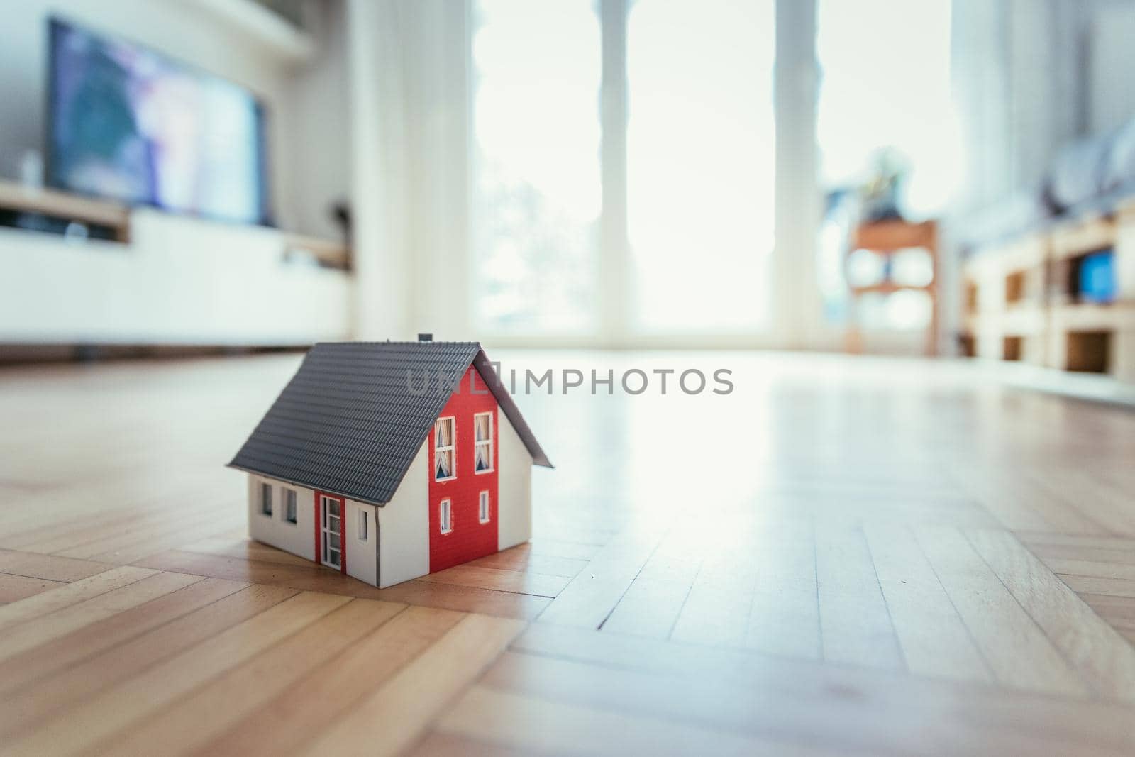 Red house model on the floor, indoors. Concept for new home, property and estate