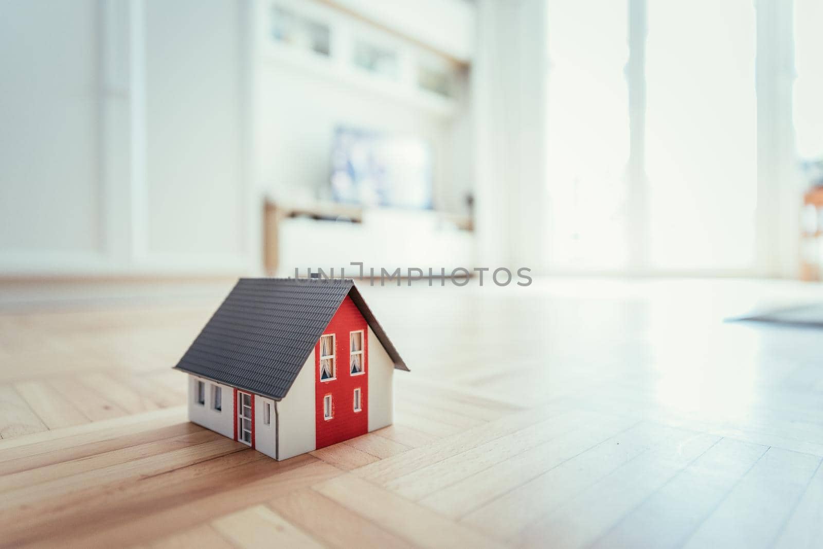 Red house model on the floor, indoors. Concept for new home, property and estate