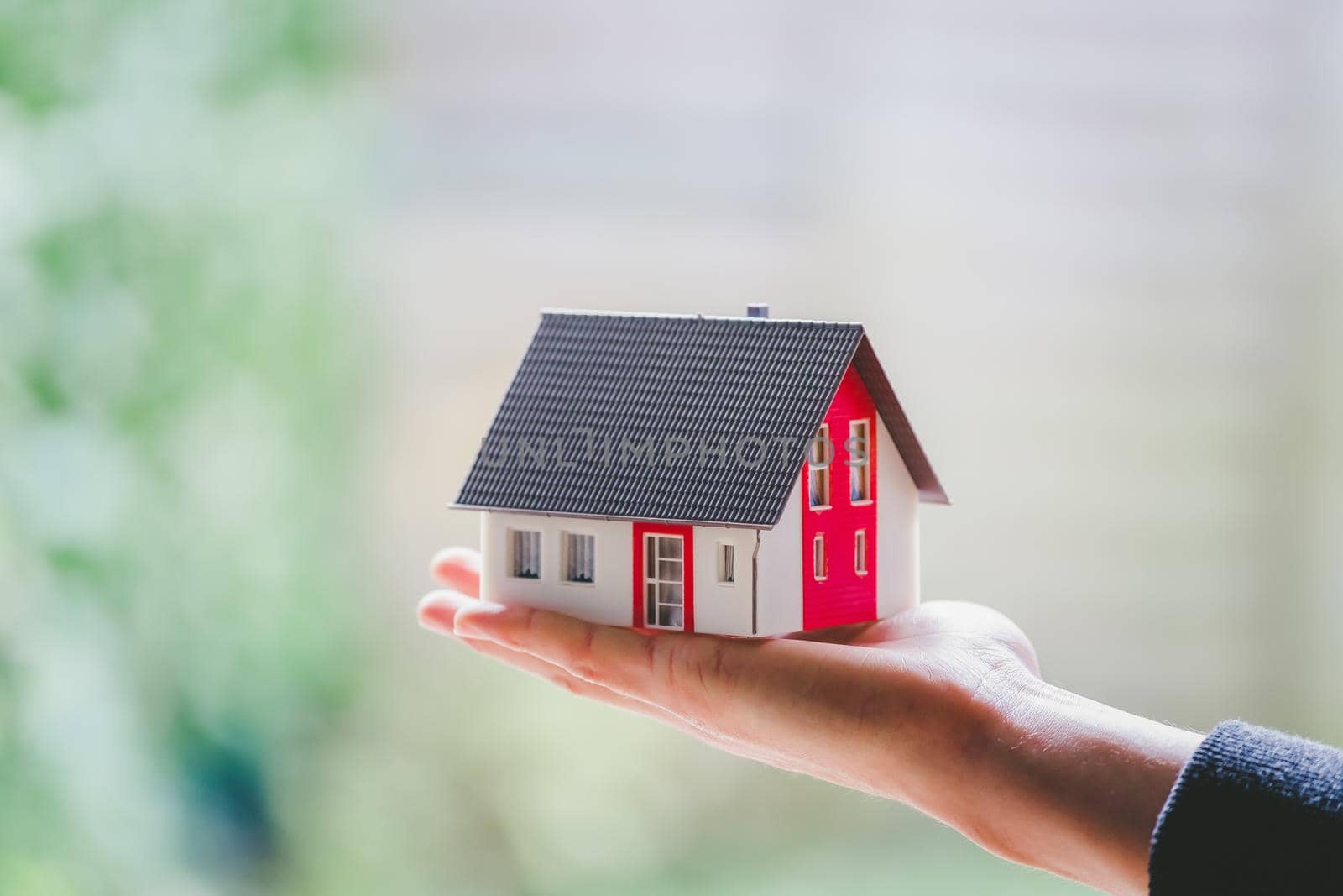 New home and house concept: Red house model outdoors in male hand