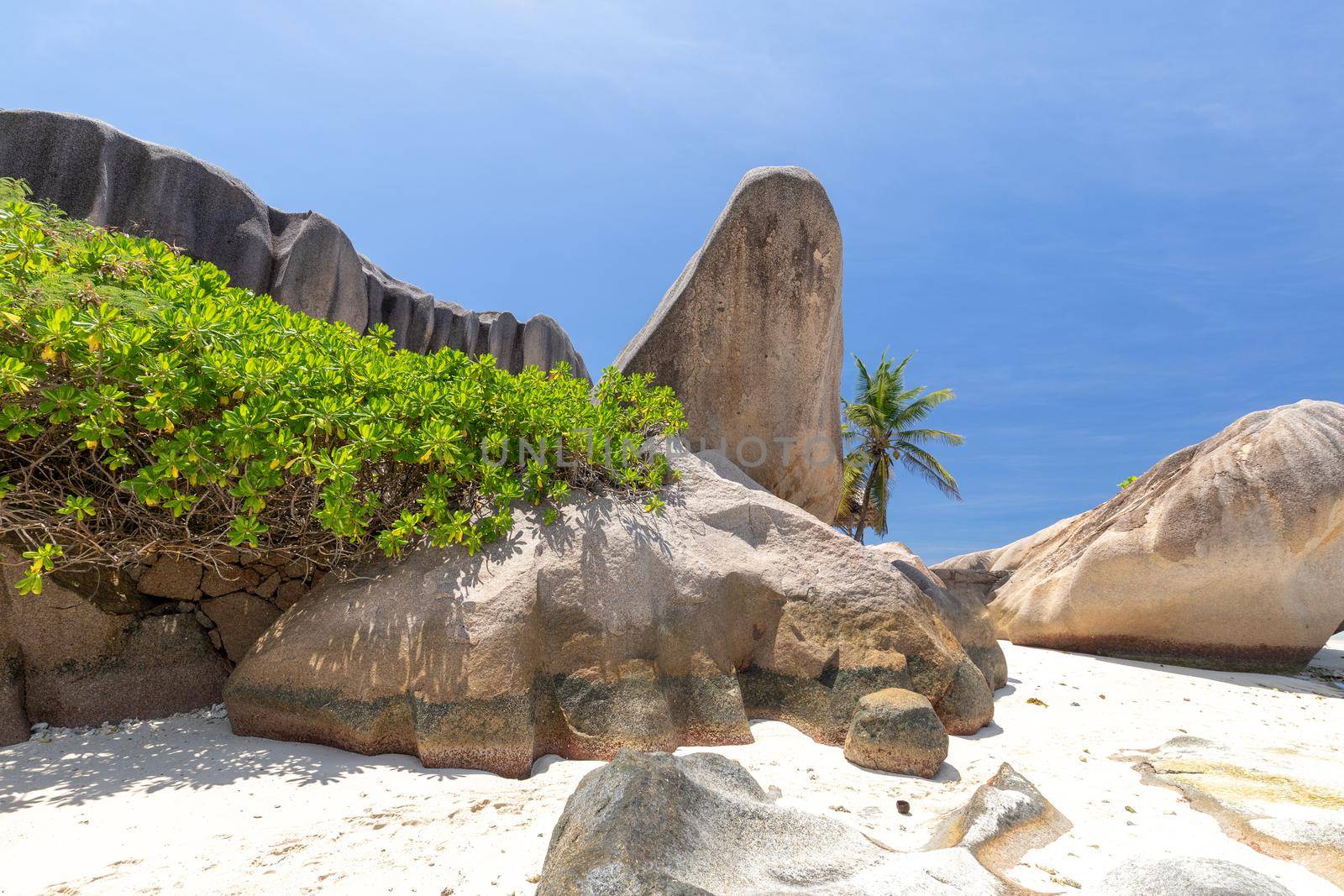 Beautiful beach Anse Source D'Argent on Seychelles island La Digue with white sand, granite rocks on the beach, wooden cottage and palm tree and blue sky 