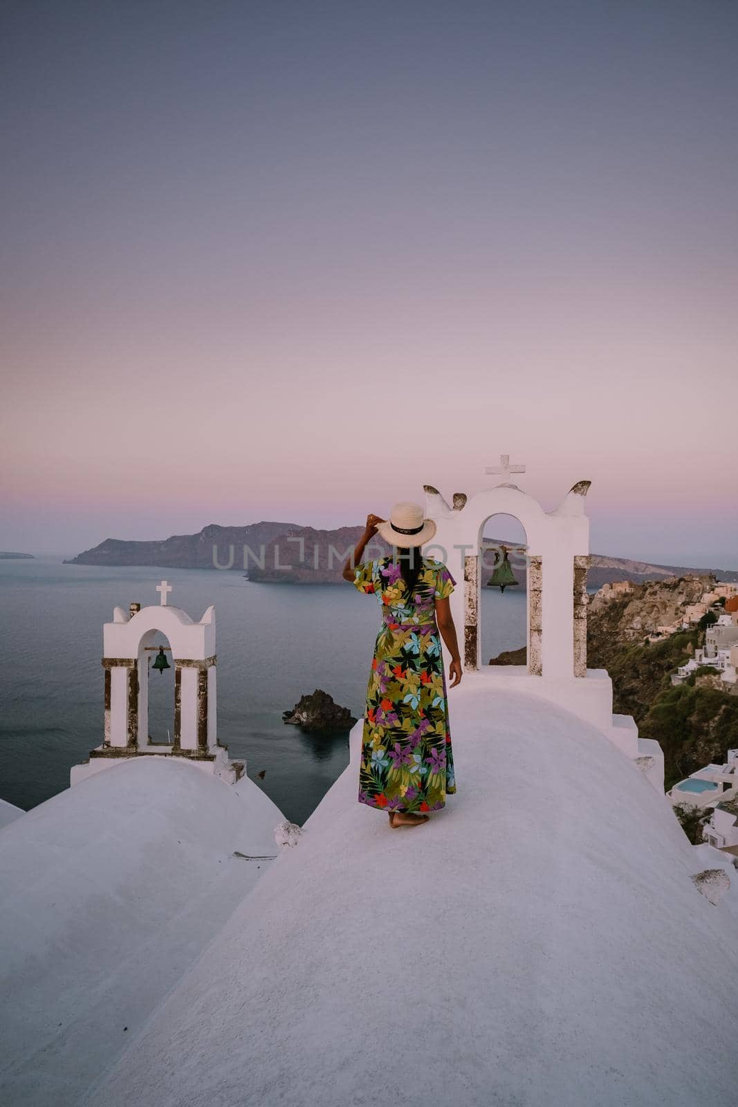 Sunset at the Island Of Santorini Greece, beautiful whitewashed village Oia with church and windmill during sunset Woman on luxury vacation Greece by fokkebok