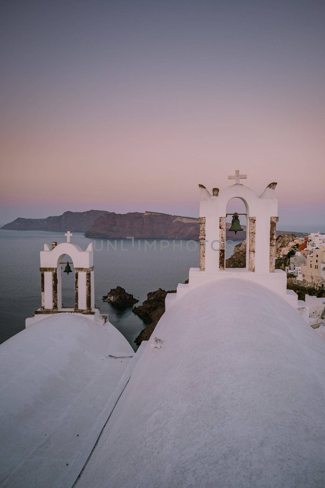 Sunset at the Island Of Santorini Greece, beautiful whitewashed village Oia with church and windmill during sunset by fokkebok