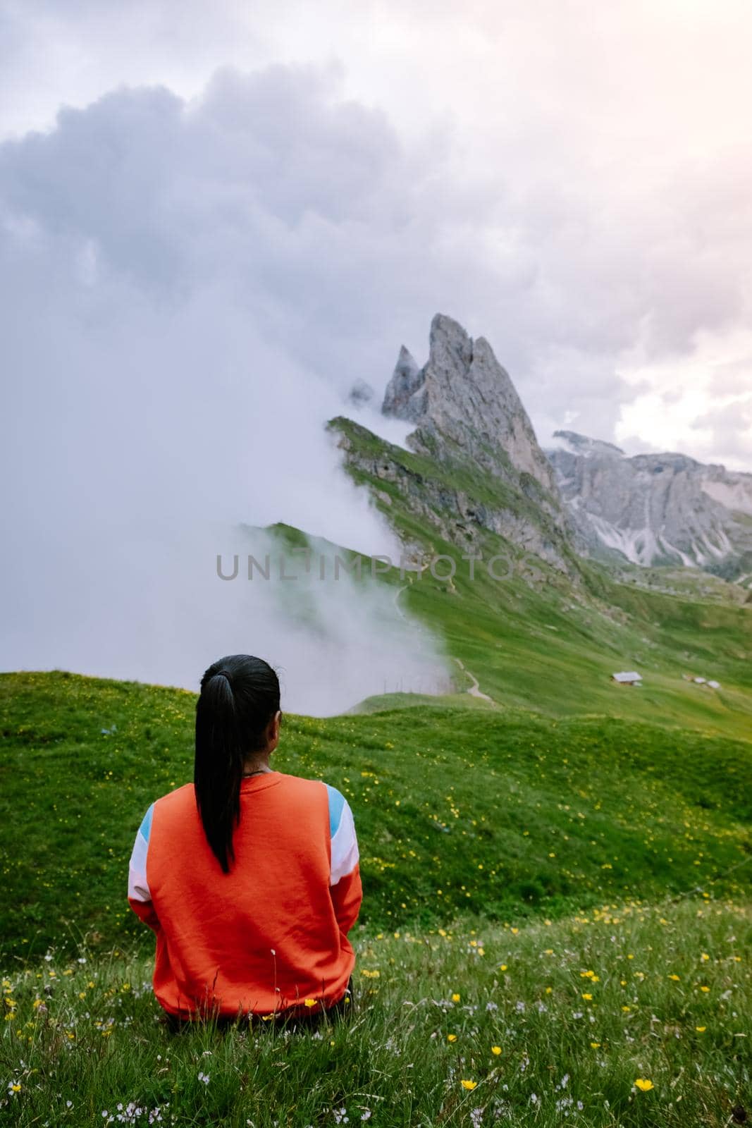 woman on vacation hiking in the Italien Dolomites, Amazing view on Seceda peak. Trentino Alto Adige, Dolomites Alps, South Tyrol, Italy, Europe. Odle mountain range, Val Gardena. Majestic Furchetta peak in morning sunlight. Italy